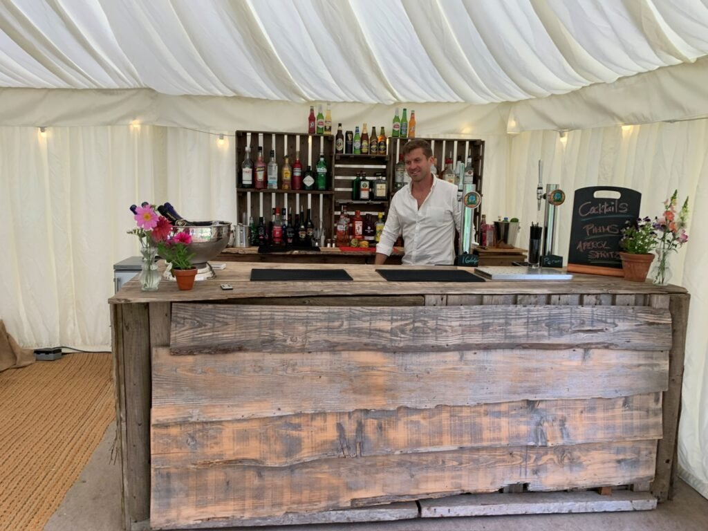 Sammy serving behind the Raise the Bar mobile bar in a marquee