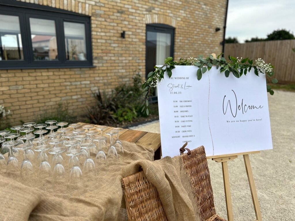 Welcome drinks glassware arranged beside a wedding welcome sign